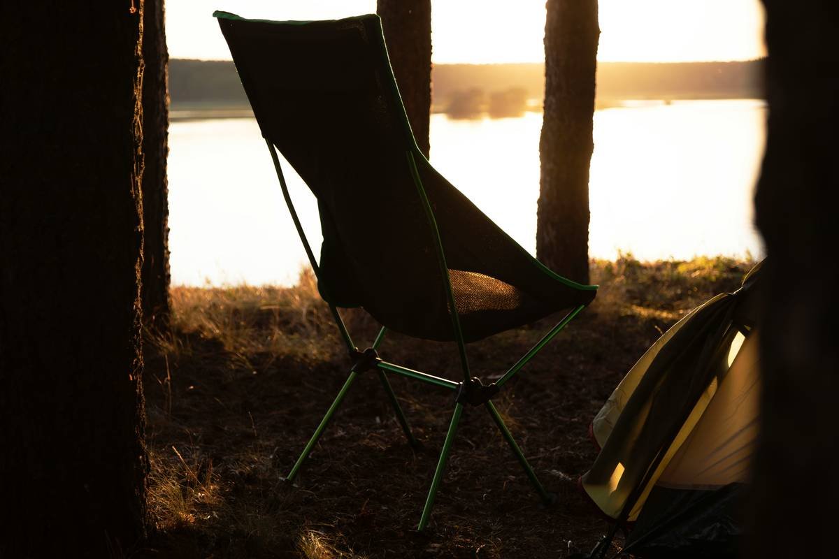 An assortment of comfortable folding chairs set up around a glowing campfire under starry skies.